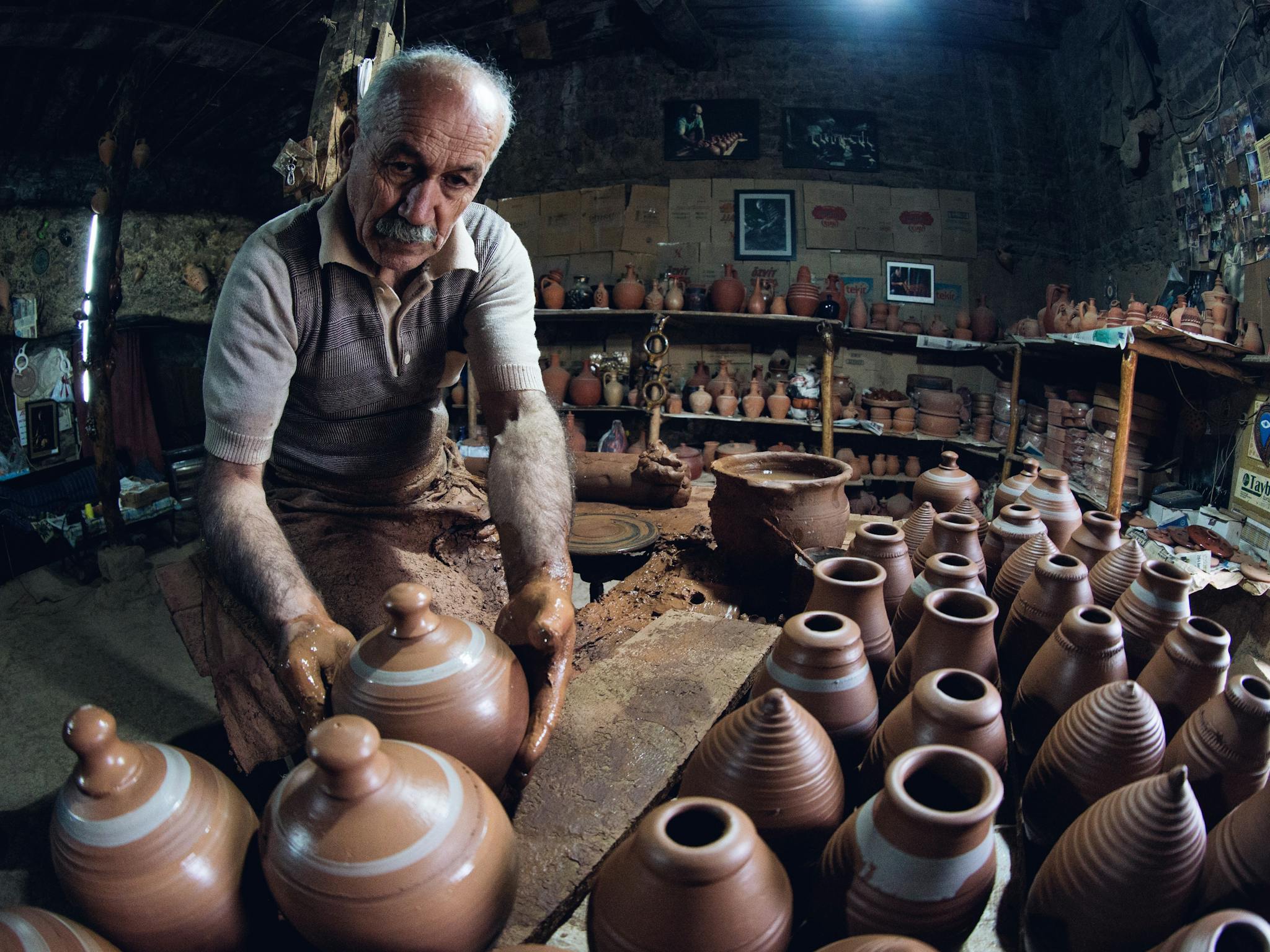 Senior man shaping clay pots in a cozy rustic pottery workshop